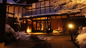 Een traditioneel Japans gebouw met een besneeuwde ingang en verlicht interieur.