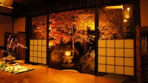 Een traditionele Japanse kamer met tatami vloeren, een shoji scherm en uitzicht op herfstbomen.