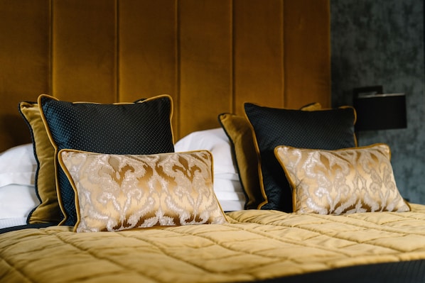 Una cama con cubierta acolchada dorada y dos almohadas con diseño dorado y negro.