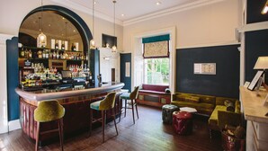 A bar area with a wooden counter, bar stools, and a seating area with a sofa and armchairs. - Saltmarshe Hall (Goole)