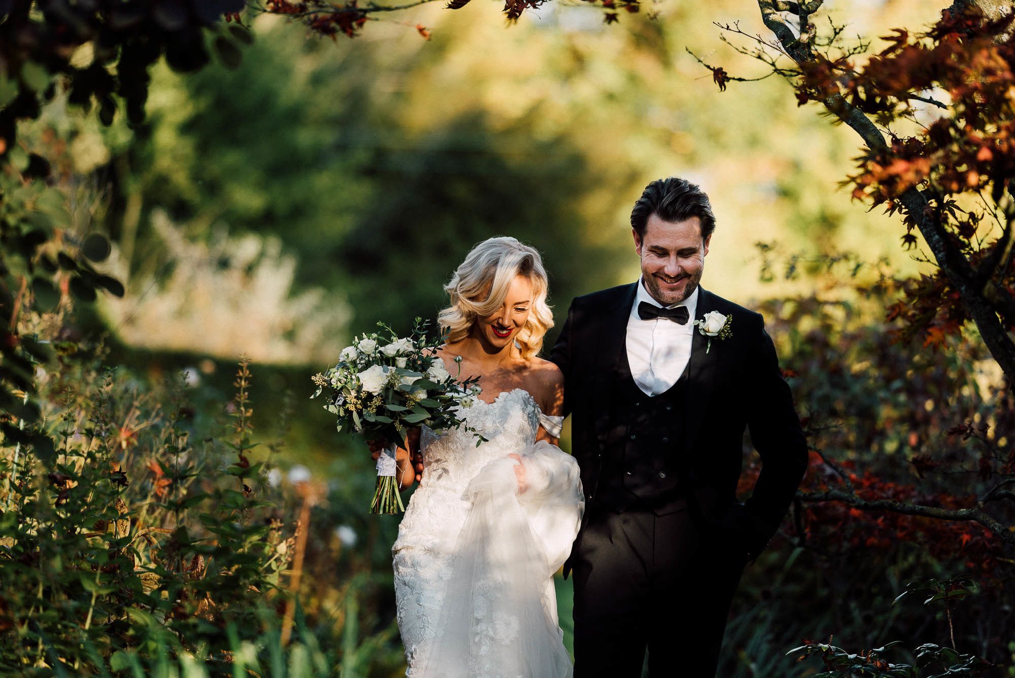 A couple in a garden setting, surrounded by greenery and trees.