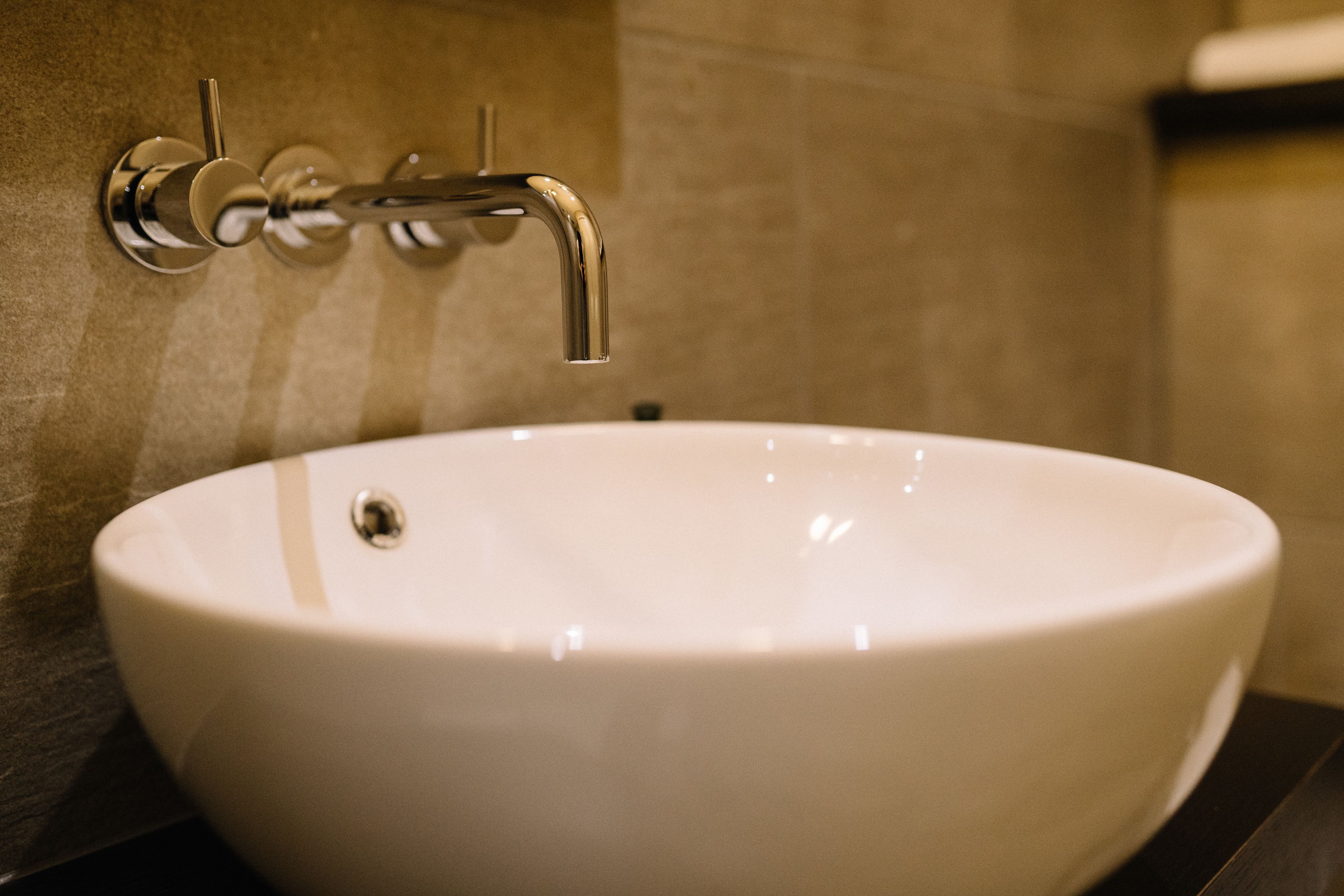 Un lavabo de cerámica blanca con un grifo de cromo instalado en una pared revestida de azulejos.