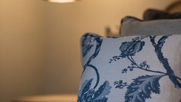 Un lit avec un oreiller à motifs et une lampe suspendue.