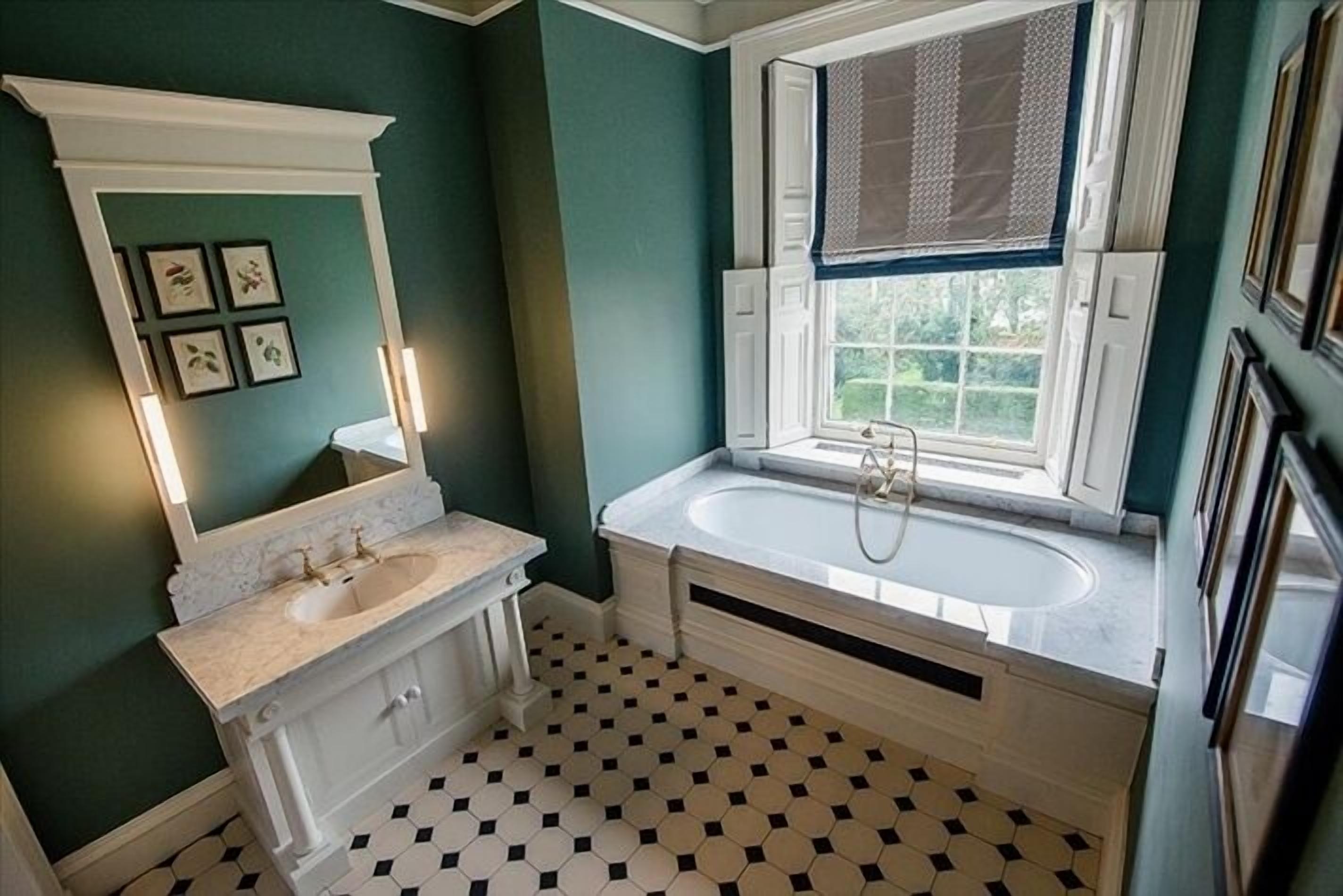 A bathroom with a white vanity, a large bathtub, and a window with a view of greenery.