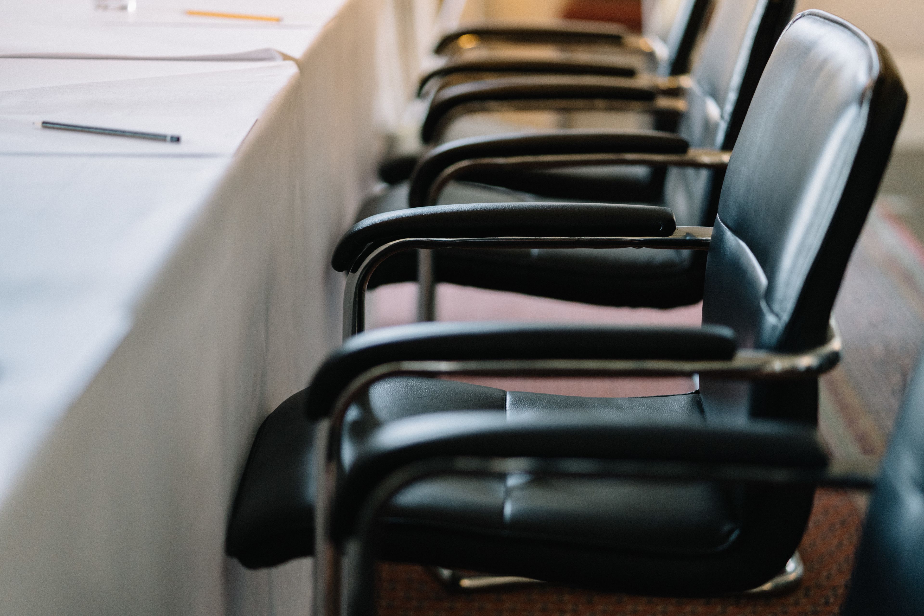 A row of black chairs with armrests, arranged in a line.