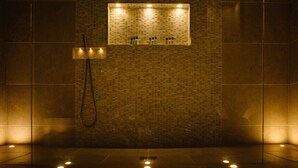 A bathroom with a tiled wall, a shower area, and a rectangular mirror with lights. - Saltmarshe Hall (Goole)