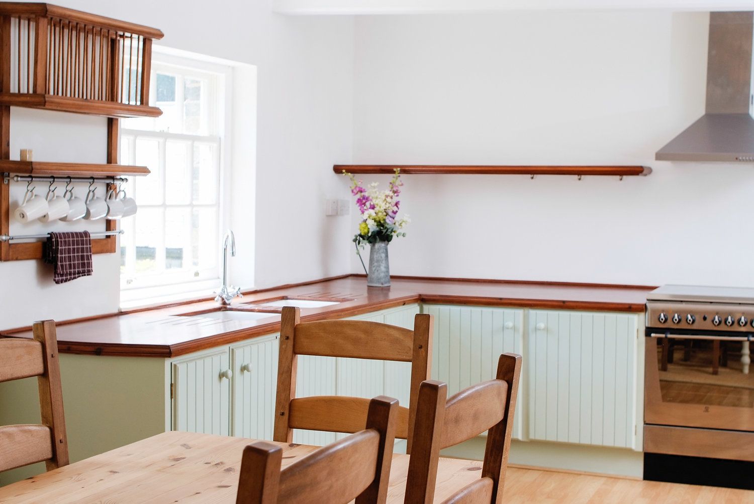 Una cocina con armarios de madera, una mesa de comedor de madera, un horno empotrado y una ventana con vistas.