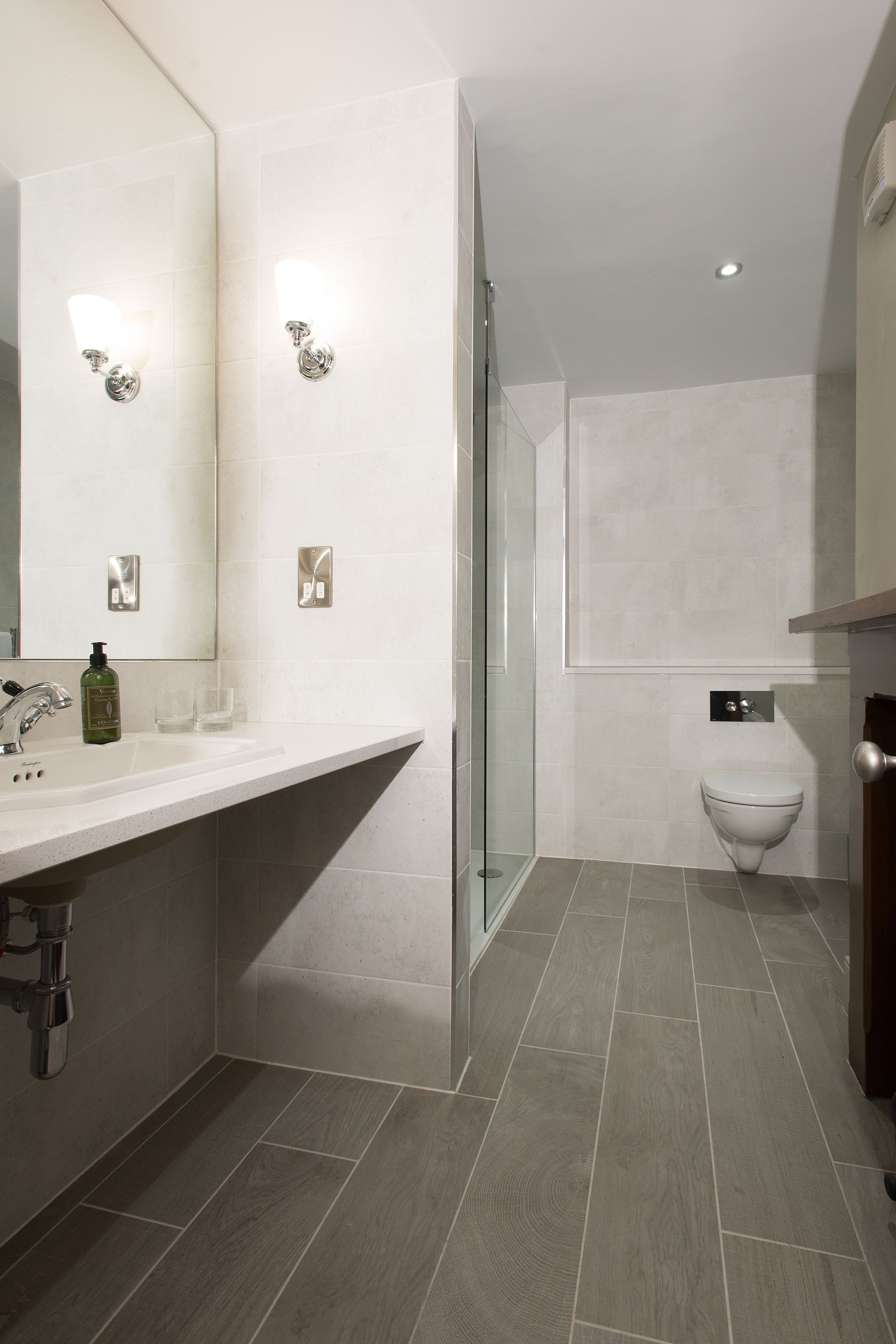 A modern bathroom with a large mirror, a sink, a toilet, and a shower area.