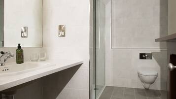 A modern bathroom with a large mirror, a sink, a toilet, and a shower area.