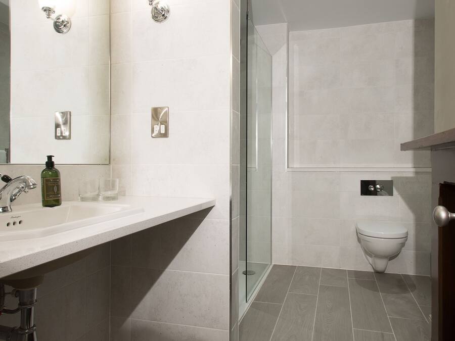 A modern bathroom with a large mirror, a sink, a toilet, and a shower area.