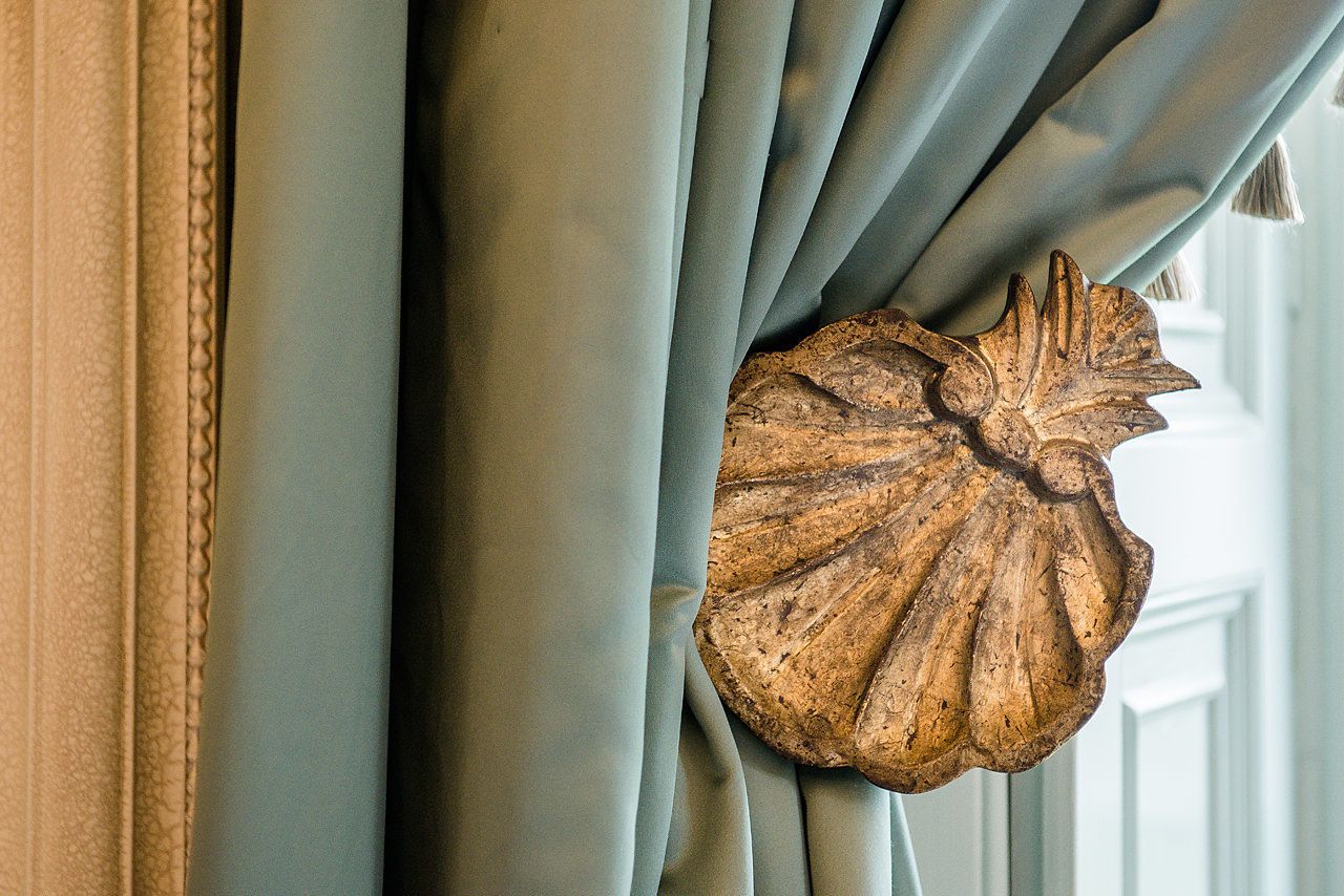 A close-up of a curtain with a wooden leaf-shaped decoration.