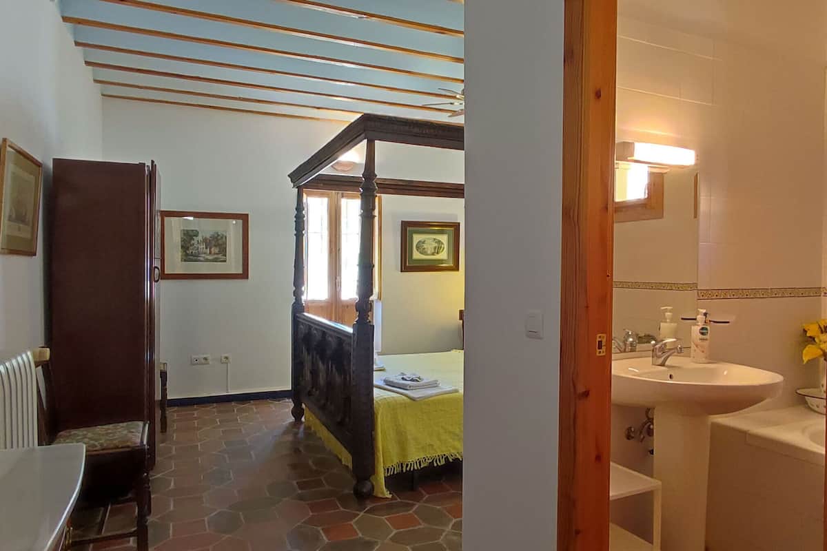 Ein Schlafzimmer mit einem Bett, einem Nachttisch, einer Kommode und einem Fenster.