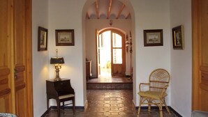 Un pasillo con puertas de madera, una lámpara, una silla y cuadros en las paredes.