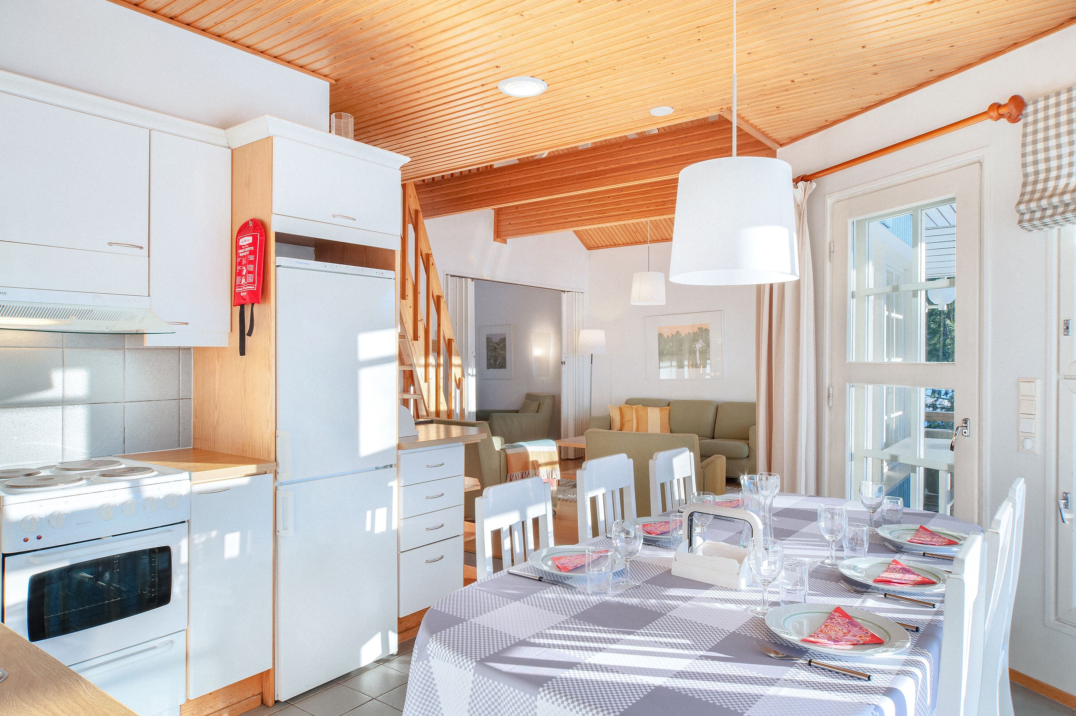 Une cuisine moderne avec des armoires blanches, un four encastré et un coin repas avec une table dressée pour quatre personnes.