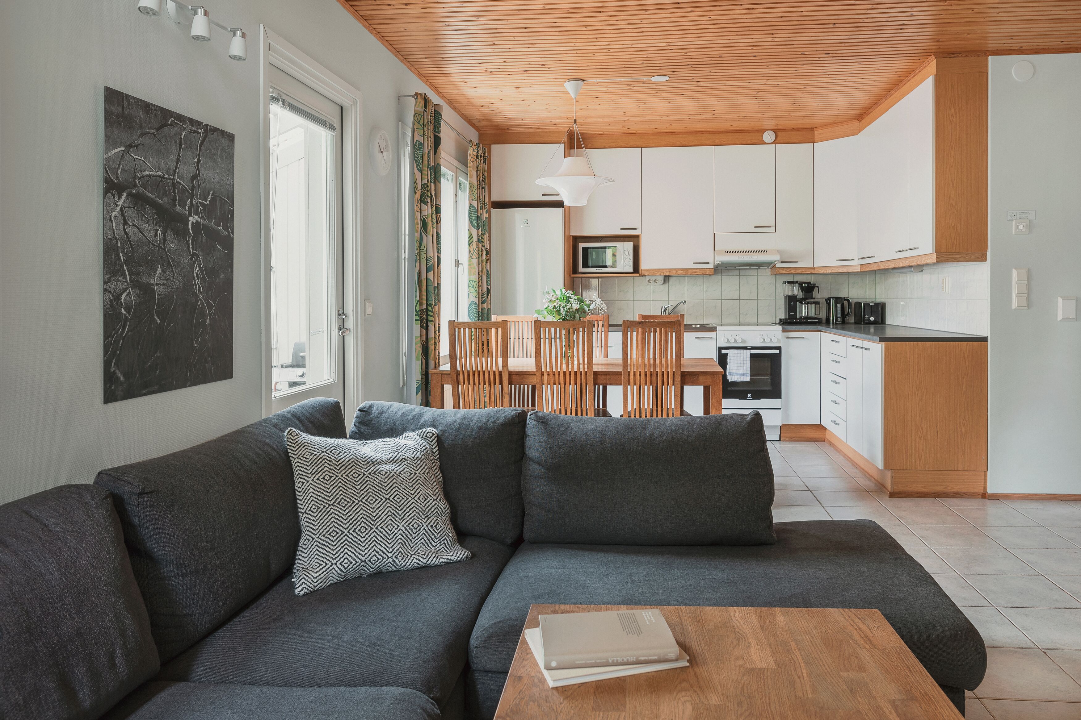 Ein modernes Wohnzimmer mit einem grauen Sofa, einem Holztisch und einem Essbereich mit einem Holztisch und Stühlen.
