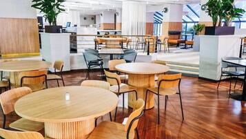 A modern interior with round tables and chairs, wooden flooring, and potted plants.