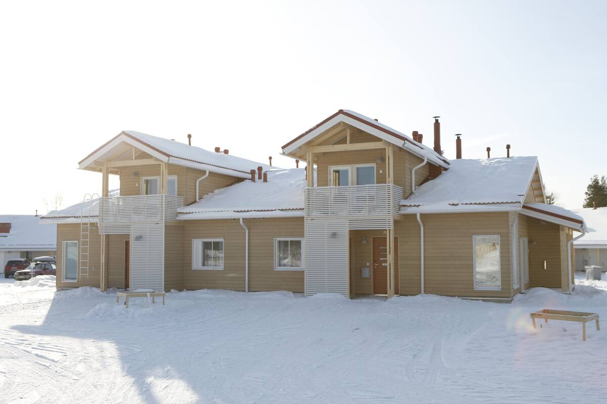 Ein zweistöckiges Holzhaus mit einem Balkon, umgeben von Schnee.