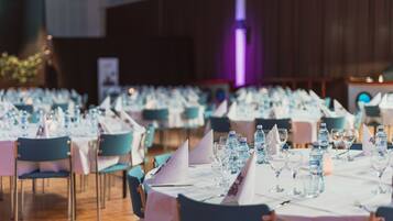 Un salón de banquetes con mesas dispuestas para un evento formal, con manteles blancos y sillas azules.