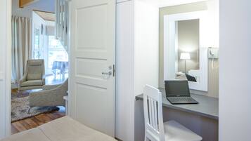 A bedroom with a bed, a desk with a laptop, a chair, and a mirror.