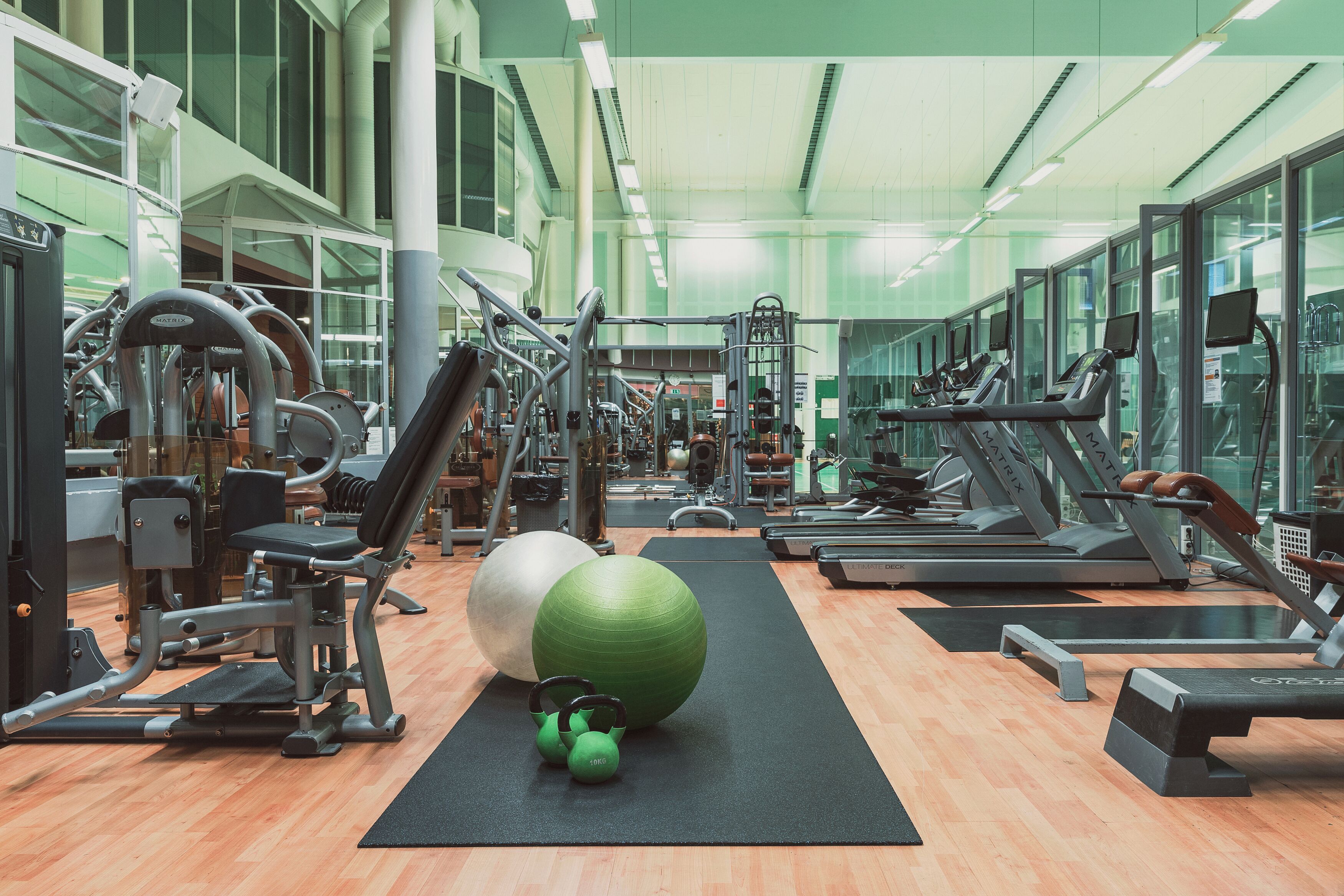 Un gimnasio con diversos equipos de ejercicio, incluyendo cintas de correr, máquinas de pesas y pelotas de entrenamiento.