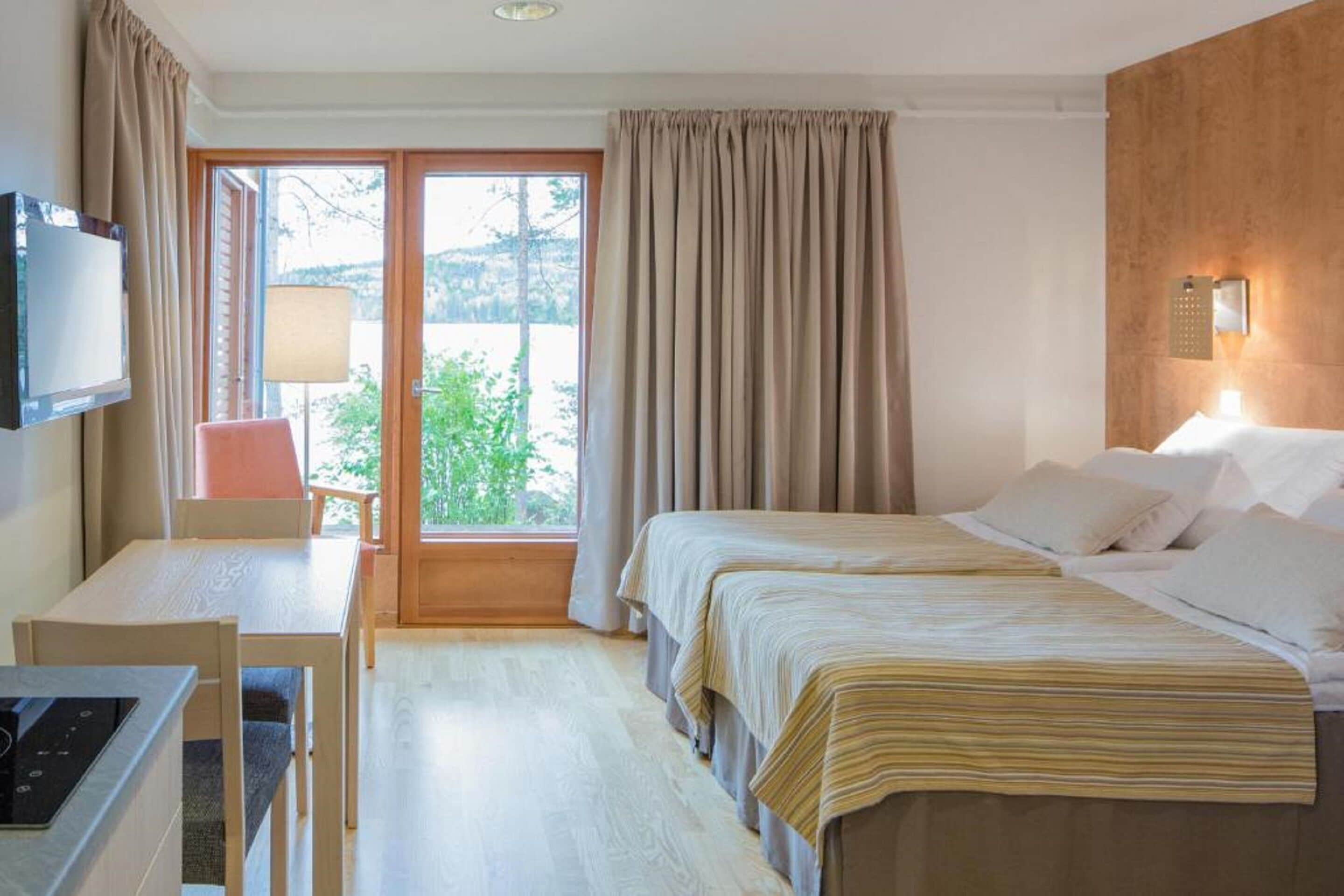 Una habitación de hotel con una cama, un escritorio, una silla y un televisor.