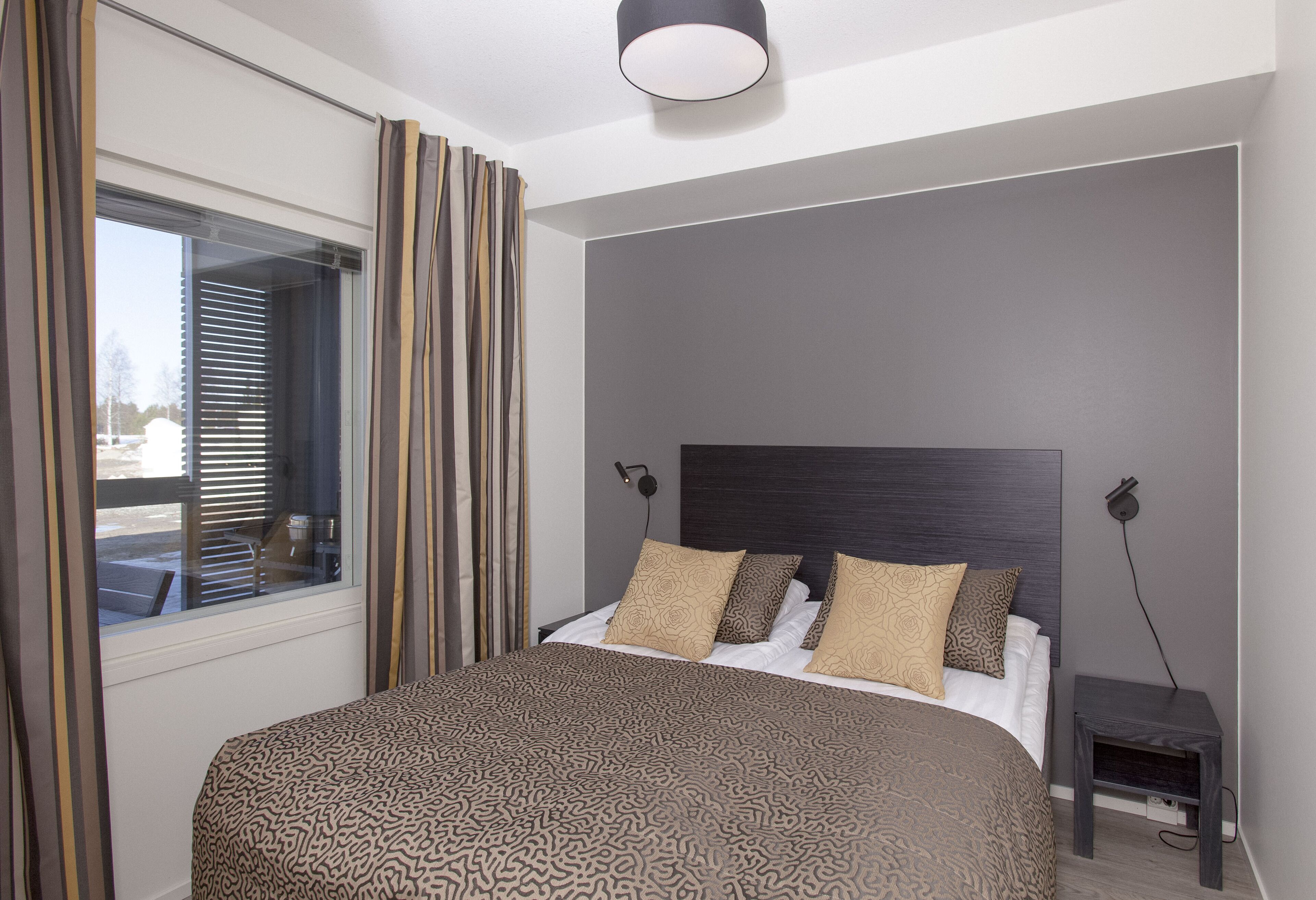 Ein modernes Schlafzimmer mit einem großen Bett, einem Kopfteil, einem Nachttisch und einem Fenster mit Vorhängen.