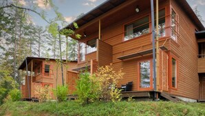 Eine moderne Holz-Blockhütte mit mehreren Ebenen, großen Fenstern und einem Balkon.