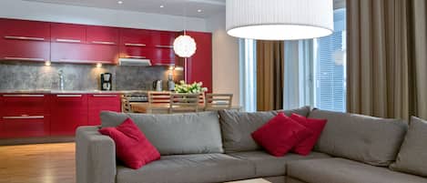 A modern living room with a grey sectional sofa, red cushions, and a wooden coffee table with apples.