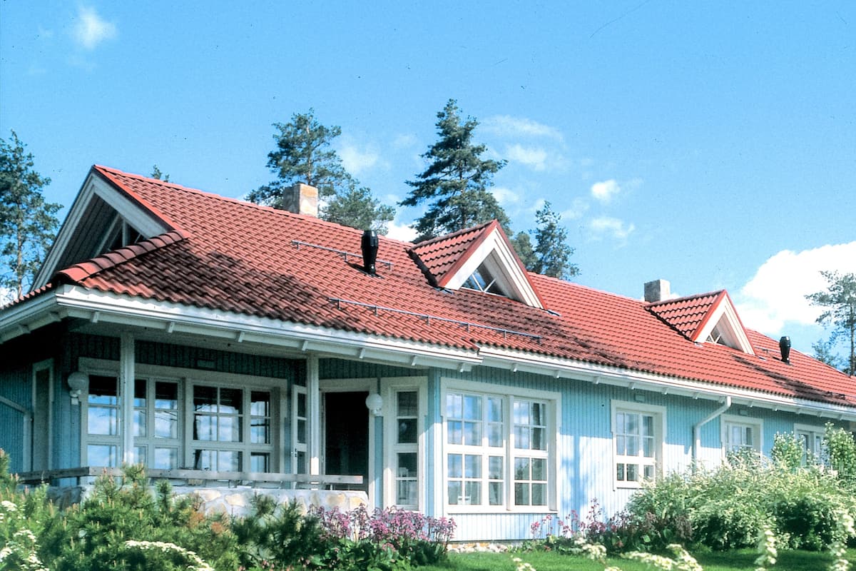 Ein großes, einstöckiges Haus mit rotem Ziegeldach, weißen Außenwänden und einer Veranda.