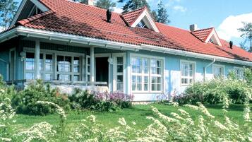 A large, single-story house with a red-tiled roof, white exterior walls, and a front porch.