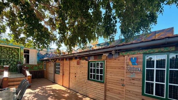Un bâtiment en bois avec des fenêtres à cadre vert et une fresque sur le mur latéral.