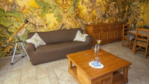 Un salon avec une fresque murale, un canapé, une table basse et un trépied.