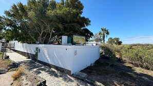 Un bâtiment blanc avec un chemin de pierre menant à une entrée fermée par un portail.