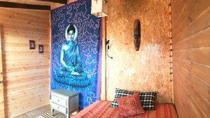 Une chambre avec un lit, un petit bureau et une tapisserie représentant une figure contemplative.