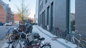 Een rij fietsen geparkeerd langs een voetpad naast een gebouw met een bakstenen gevel.