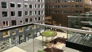 Een modern gebouw met meerdere verdiepingen, grote ramen en een centrale binnenplaats met een rond zitgedeelte.