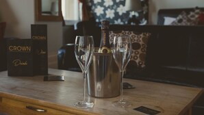 A wooden table with a bottle of Crown wine and two glasses, a box labeled "Crown Wine," and a sign with "Crown" on it. - The Crown Hotel (Morecambe)