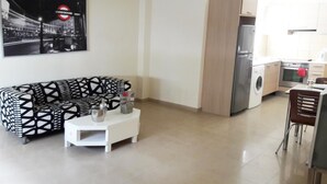 A modern living room with a black and white patterned sofa, a small white coffee table, and a kitchen area with a washing machine and oven. - Ledras Town Center (Nicosia)