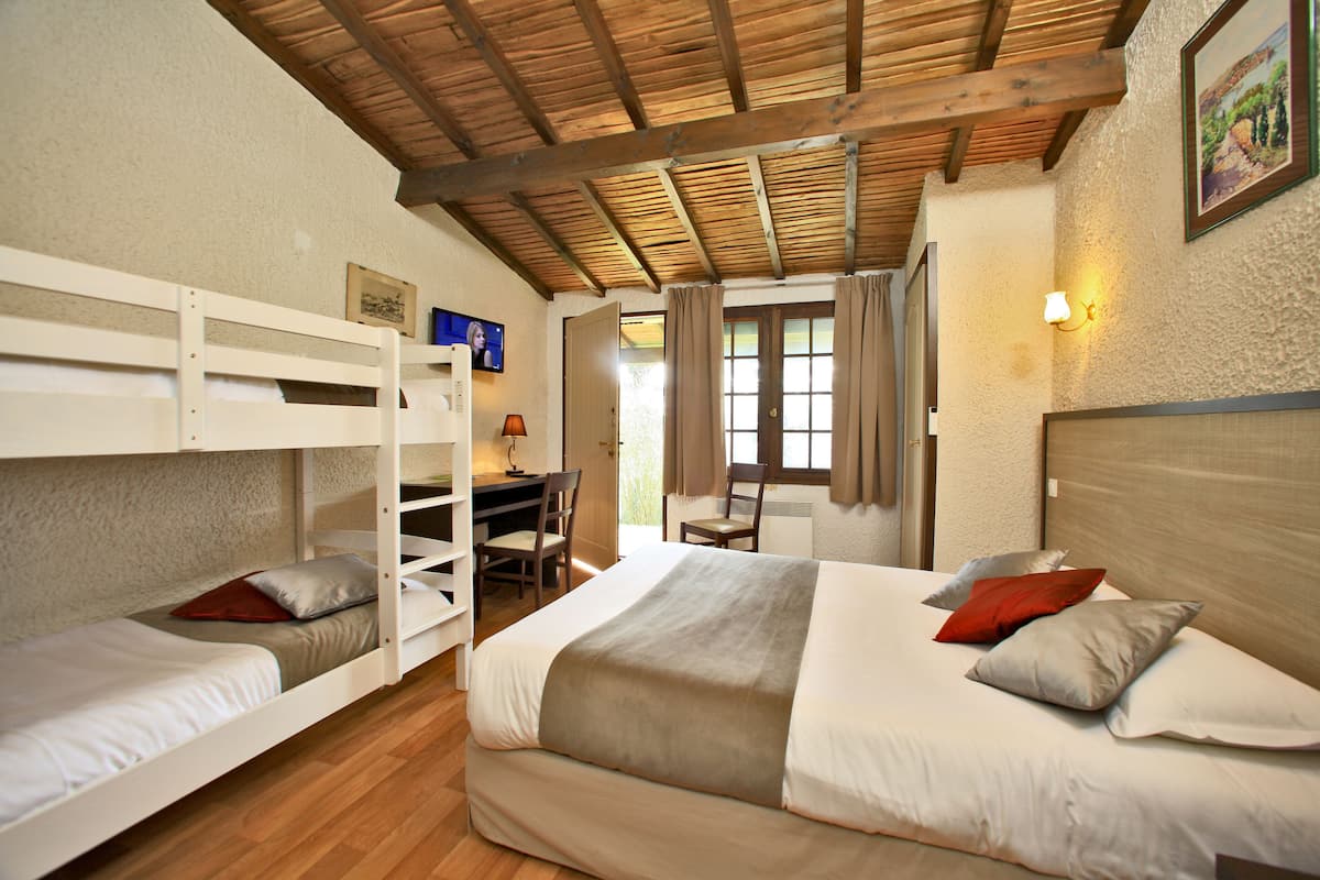 A room with a bunk bed, a desk, and a chair, with a window and curtains.