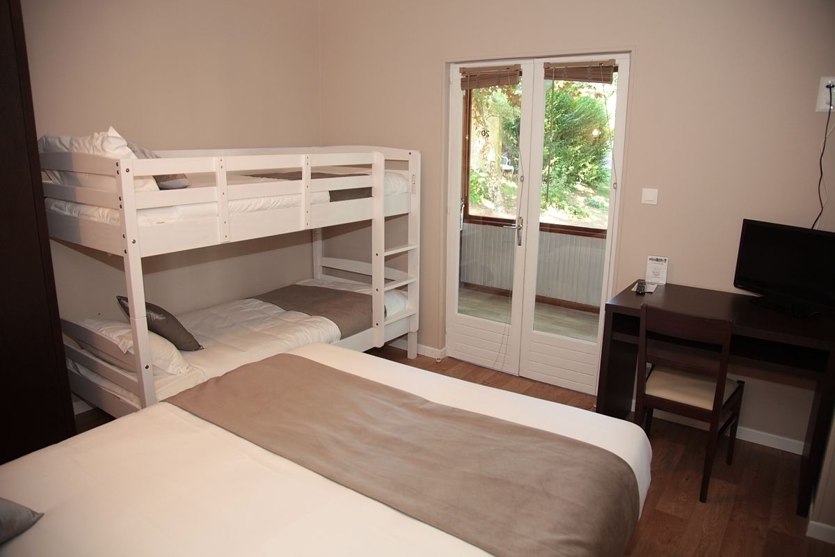 A room with bunk beds, a desk, a television, and a sliding glass door leading to an outdoor area.