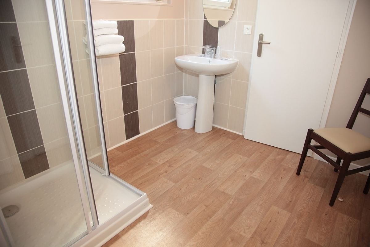 Ein Badezimmer mit Dusche, Waschbecken und Stuhl.