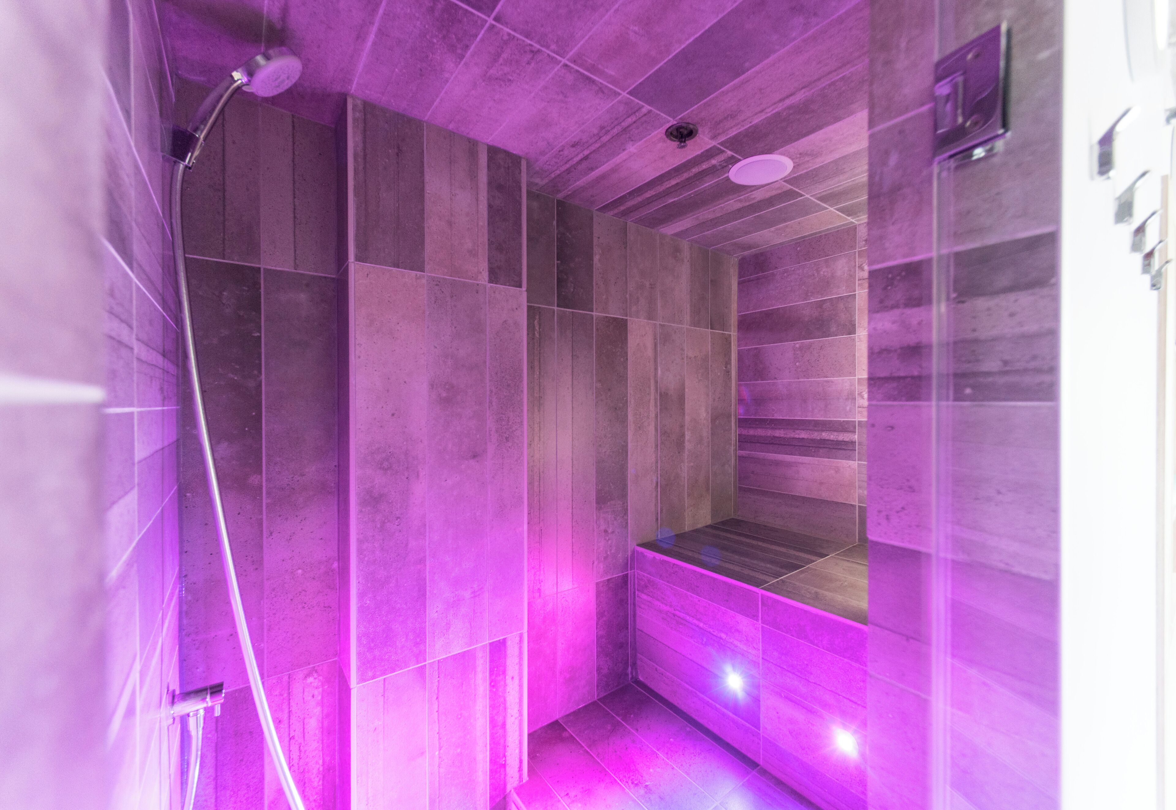 Un baño moderno con ducha, paredes con azulejos y un banco.