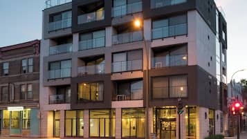 Um edifício de vários andares com design arquitetônico moderno, com varandas e grandes janelas.