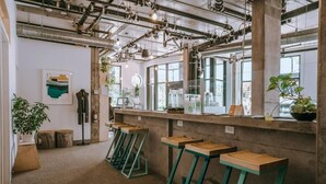 Un espace bar moderne avec des murs en béton, des tabourets en bois et un éclairage de style industriel.