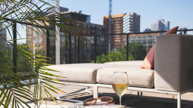 Un espace de détente extérieur moderne, avec un canapé, un verre de vin blanc et un livre.