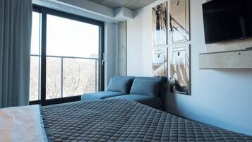 A hotel room with a large bed, a smaller bed, a TV, and artwork on the wall.