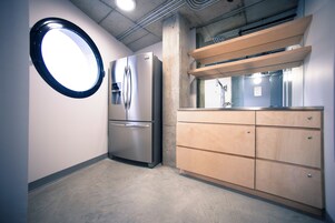 A compact kitchen with a built-in refrigerator, wooden cabinets, and a round mirror.
