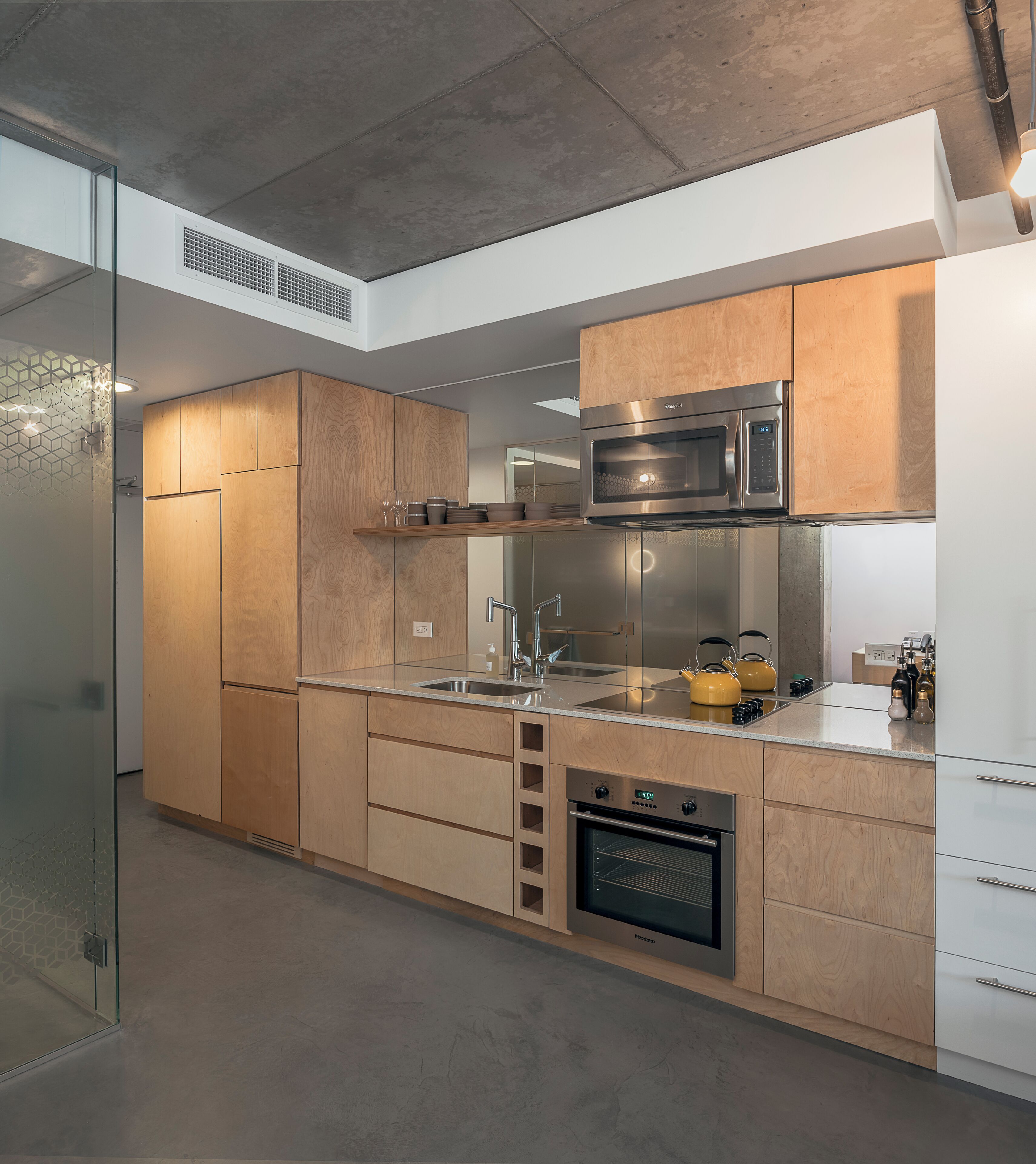 Een moderne keuken met houten kastjes, roestvrijstalen apparatuur en een glazen spatwand.