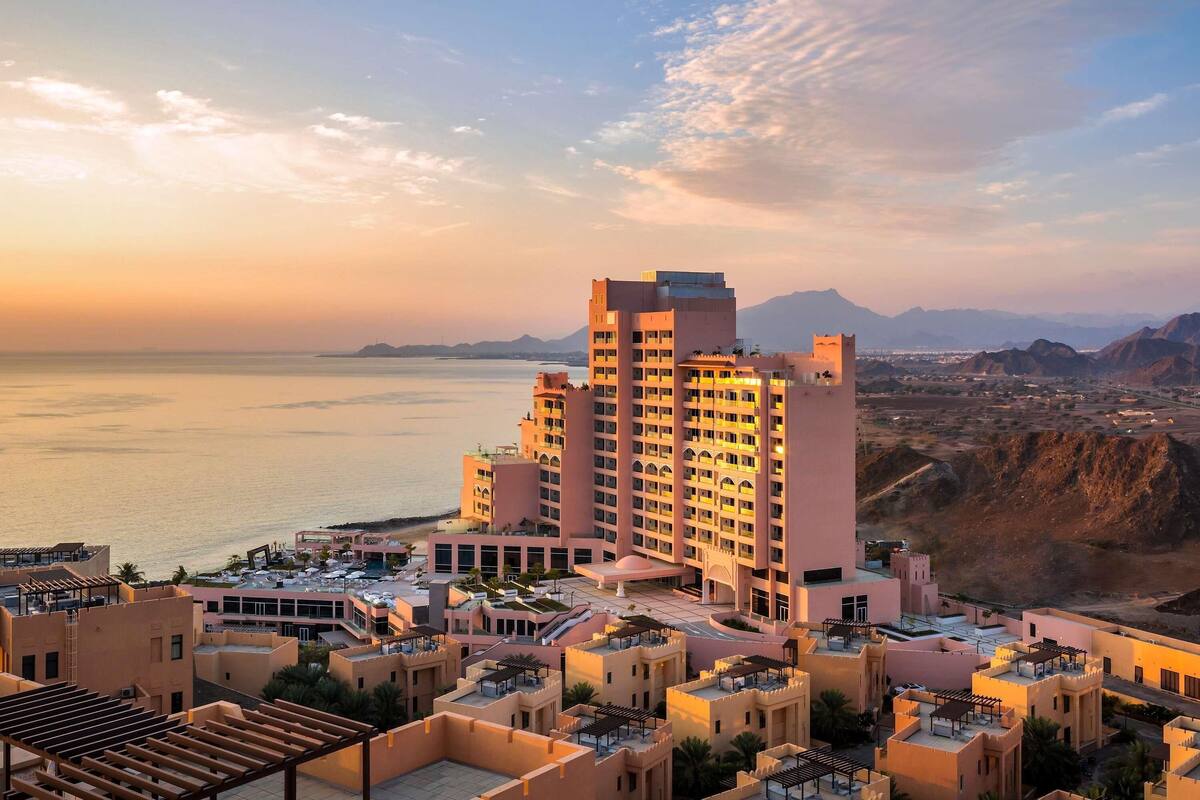 Un hôtel composé de plusieurs bâtiments, doté de terrasses sur le toit et offrant une vue sur la mer et les montagnes.