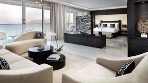Una habitación de hotel moderna con un balcón grande, una cama con cabecera, una mesita de café y un televisor montado en la pared.